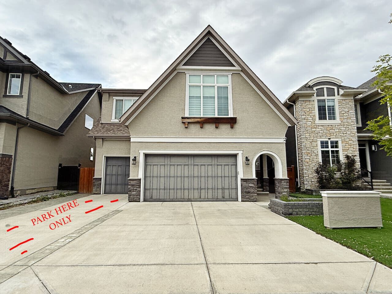 A modern two-story house with a large garage, a stone accent wall, and a well-maintained lawn.