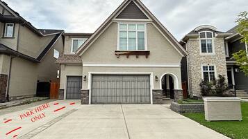 A modern two-story house with a large garage, a stone accent wall, and a well-maintained lawn.