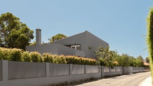 Une maison moderne avec un toit plat, de grandes fenêtres et un mur en béton.