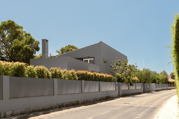 A modern house with a flat roof, large windows, and a concrete wall.