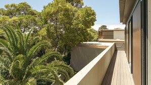 Un balcon donnant sur des arbres, avec un bâtiment visible au loin.