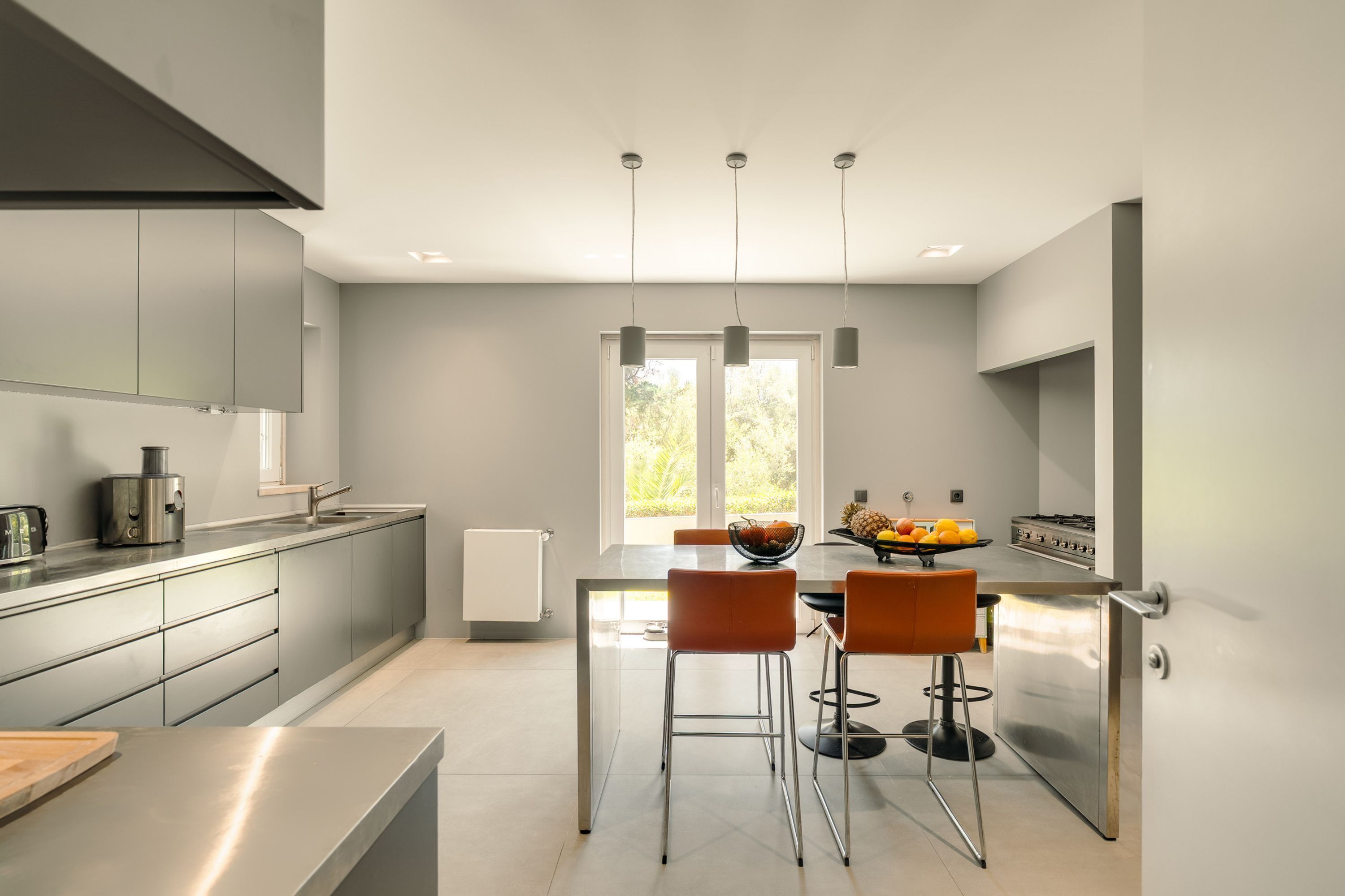 A modern kitchen with a central island, stainless steel appliances, and a large window providing natural light.