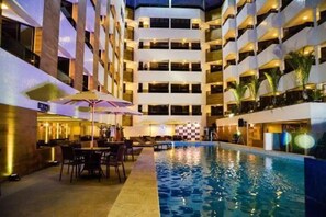 Interior de un hotel con piscina, varios pisos y zonas de estar al aire libre.
