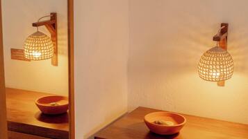 Uma mesa de cabeceira de madeira com uma tigela e uma luminária fixada na parede.