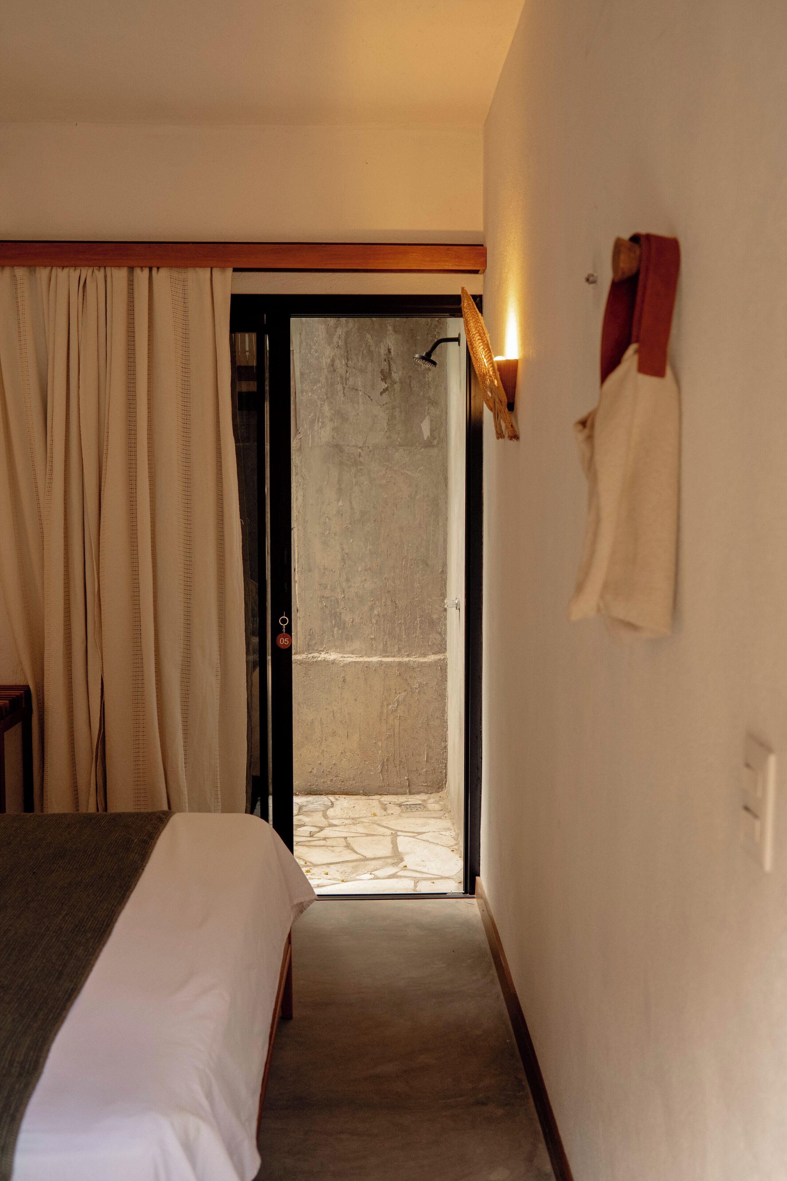 Een hotelkamer met een bed, een deur naar een balkon en een handdoek aan de muur.