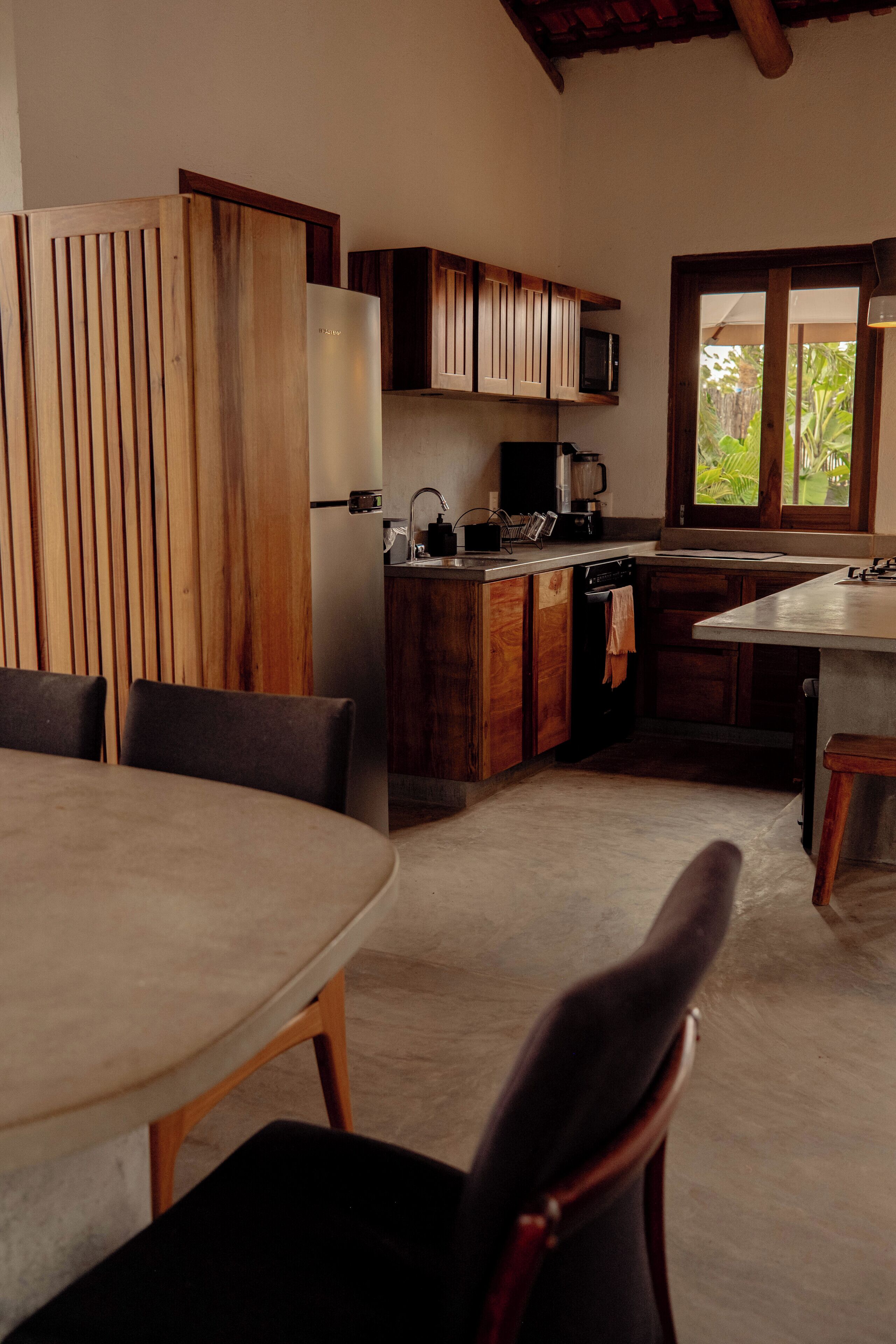 A kitchen with wooden cabinets, a microwave, and a window with a view of greenery.