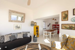 A living room with a sofa, a dining table with chairs, a yellow bookshelf, and a red cabinet.