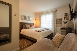 Une chambre à coucher avec un lit, une table de chevet, une lampe et un miroir.