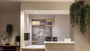 A reception desk with a Holiday Inn Express sign, a plant, and a staircase. - Walk to Times Square + Free Breakfast & Wi-Fi (New York)
