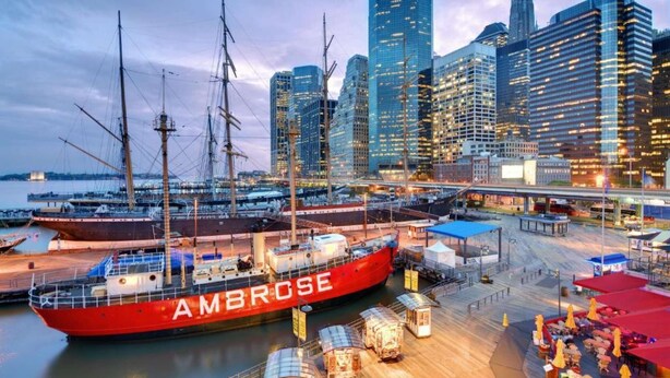 A large red ship docked at a port with a city skyline in the background. - Steps from Wall Street | Free Breakfast. Gym (New York)
