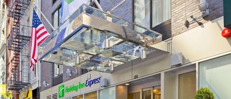 A Holiday Inn Express hotel with a glass entrance canopy, large windows, and potted plants.