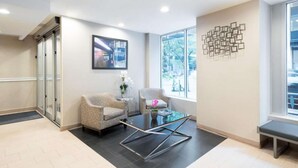 A modern waiting area with two armchairs, a glass coffee table, and a bench. - Steps from Wall Street | Free Breakfast. Gym (New York)
