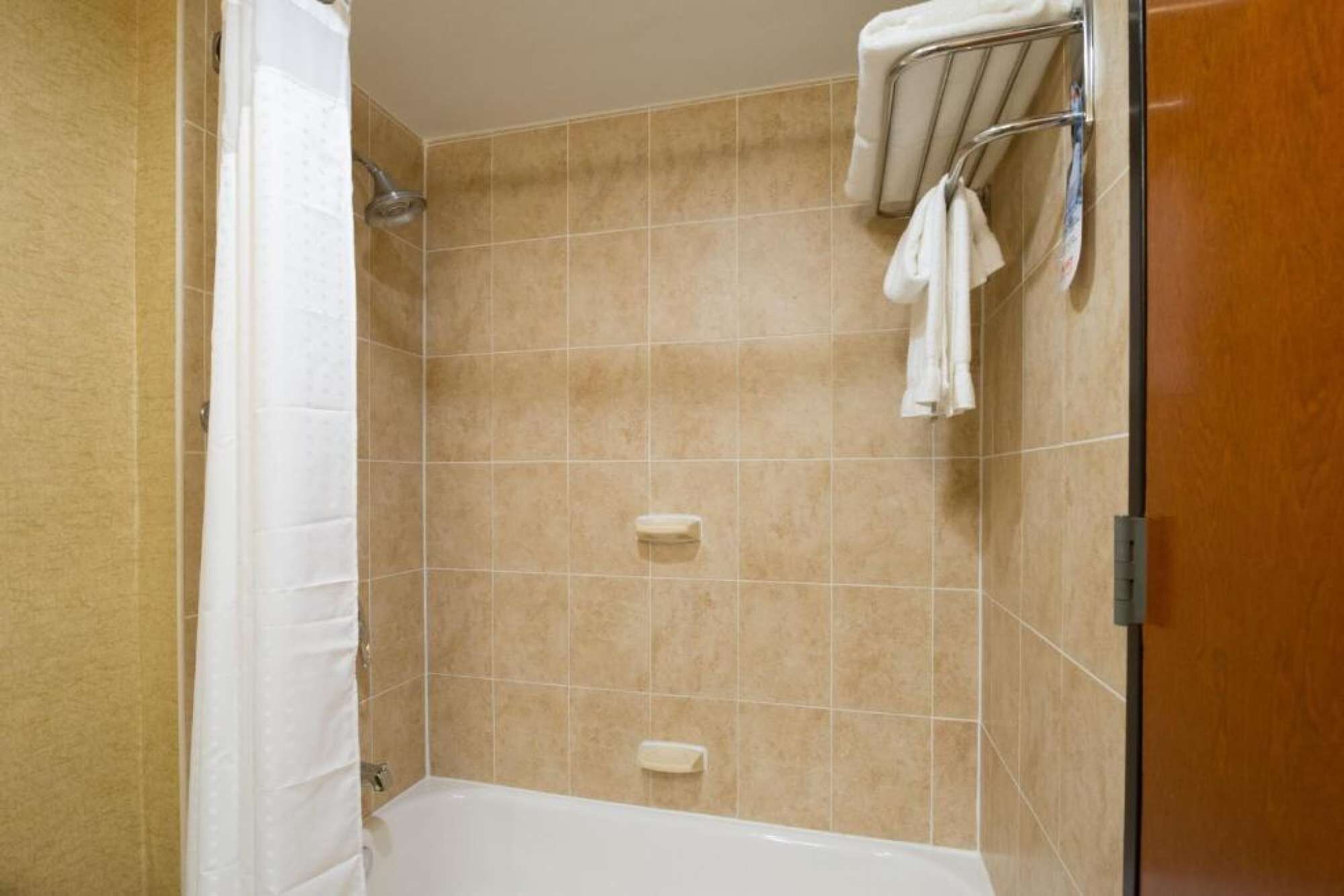 A bathroom with a bathtub, a shower, and a towel rack.