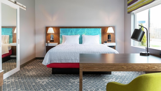 A hotel room with a bed, bedside tables, a desk, a chair, and a window with curtains. - Hampton Inn & Suites By Hilton Durango Downtown Area (Durango)