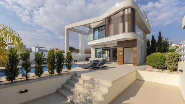 A modern two-story house with a swimming pool, outdoor seating, and a staircase leading to the upper level.