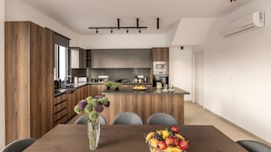 A modern kitchen with dark cabinets, a central island, and a dining area with a table set for two.