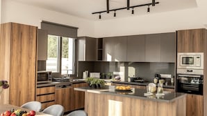 A modern kitchen with wooden cabinets, a central island, and built-in appliances.