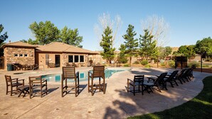Un patio trasero con piscina, mobiliario de jardín y una edificación de piedra.