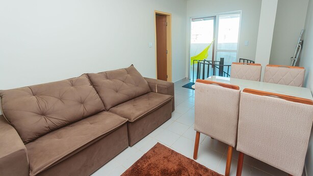 Ein Wohnzimmer mit einem braunen Sofa, einem Esstisch mit Stühlen und Blick auf einen Balkon.