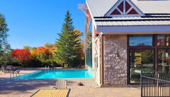 A pool area with lounge chairs and a stone building with a metal roof.