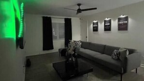 A living room with a grey sofa, a coffee table, and a ceiling fan.