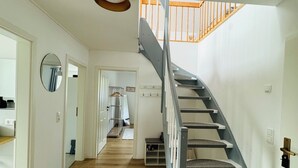 Un escalier moderne, avec des marches en bois et une rampe en métal, menant à l’étage supérieur.