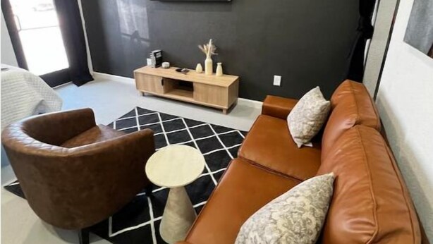 Un salón moderno con un sofá de cuero marrón, una mesita redonda pequeña y una alfombra blanco y negro.