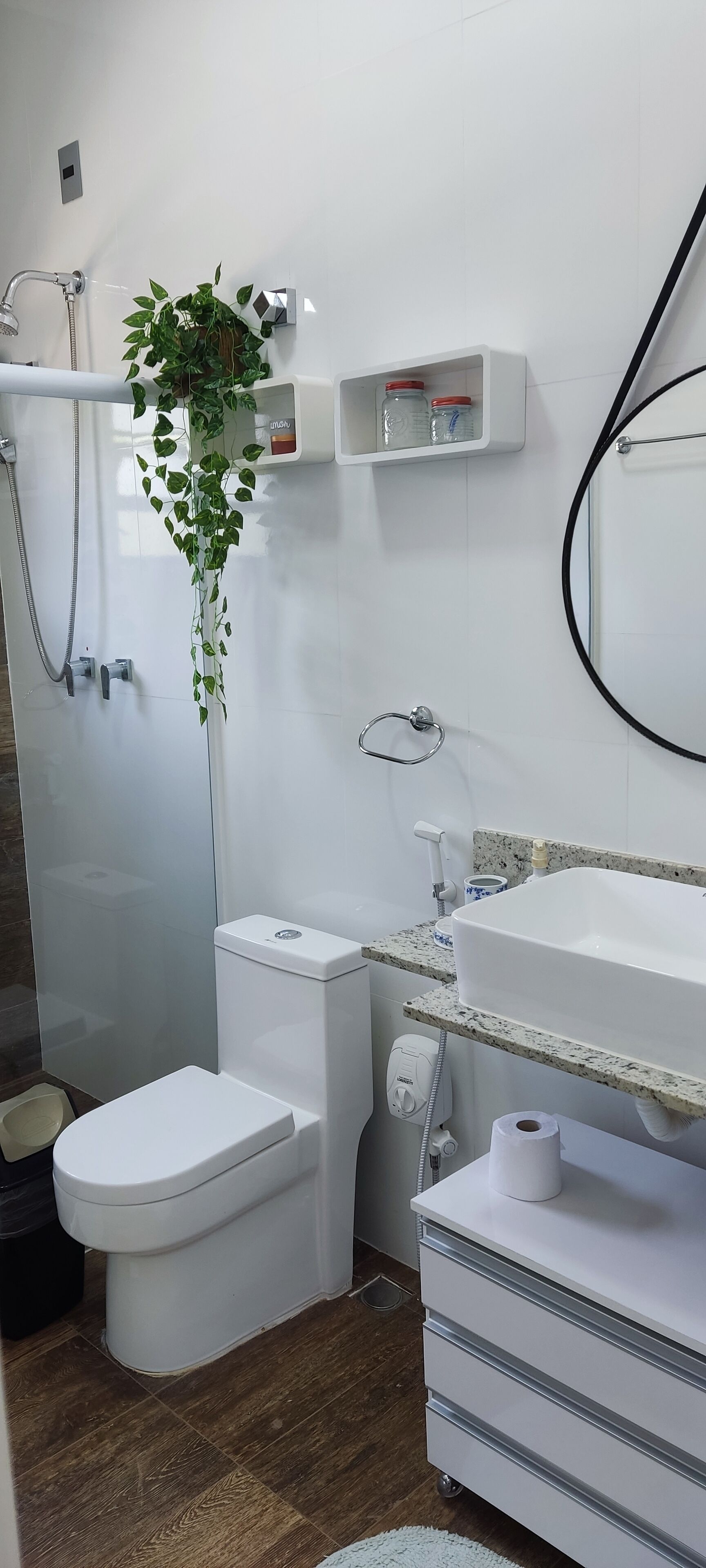 A modern bathroom with a toilet, shower, and sink.