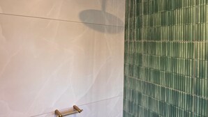 A shower with a rain-like water feature, a towel rack, and a green tiled wall. - Newly renovated, charming studio in central Jeffreys Bay with AC, WiFi, parking (Jeffreys Bay)