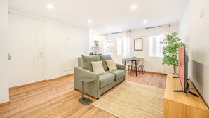 Una sala moderna con un sofá verde, una mesa de comedor y un mueble para la televisión.
