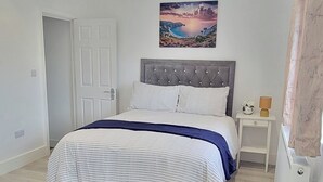 A bedroom with a bed, a nightstand, a painting, and a door.