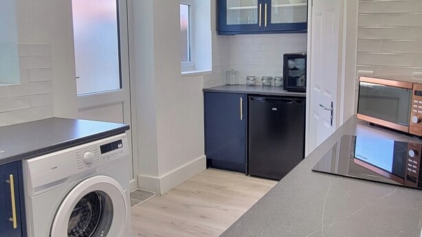 A modern kitchen with a washing machine, microwave, and built-in oven.