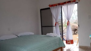 Une chambre à coucher avec un lit, une fenêtre avec des rideaux et une vue sur l’extérieur.