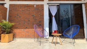 Une terrasse avec deux chaises en fil de fer, une petite table en bois et une plante en pot.