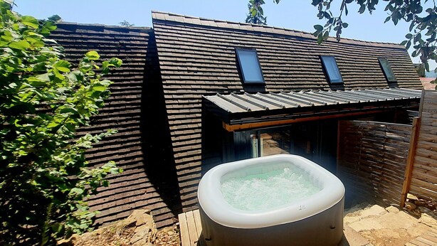 A spa area with a hot tub, wooden deck, and a brick wall. - Private Jacuzzi, F2 garden apartment + separate rupestral room. Near Sarlat (Carsac-Aillac)