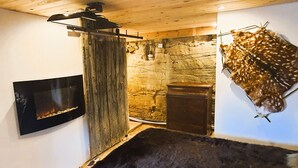 A rustic room with a stone wall, a mounted fur piece, a fireplace, and a wooden ceiling. - Private Jacuzzi, F2 garden apartment + separate rupestral room. Near Sarlat (Carsac-Aillac)