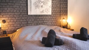 A neatly made bed with a white textured blanket and two rolled-up towels on the bed. - Chalet in Veluwe Near Kootwijkerzand (Putten)