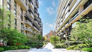 A modern urban apartment building with multiple balconies, a central pathway, and surrounding greenery. - Chic 2 Bed Apartment with AC, WiFi by London's Tower Bridge (London)