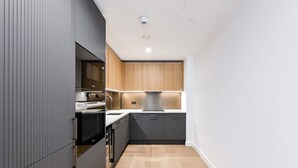 A modern kitchen with grey cabinetry, a built-in oven, and a sink. - Chic 2 Bed Apartment with AC, WiFi by London's Tower Bridge (London)