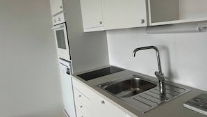 A kitchen with white cabinets, a stainless steel sink, and a built-in oven. - Helsinki City or Airport 16min, Convenience Place (Vantaa)