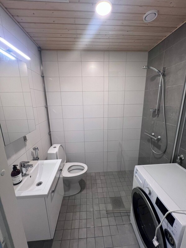 A compact bathroom with a toilet, sink, and a built-in washing machine. - Helsinki City or Airport 16min, Convenience Place (Vantaa)