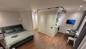 A modern bedroom with a bed, a desk, and a TV.