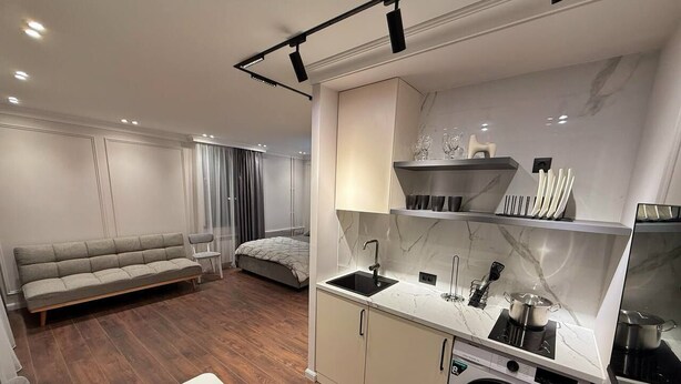 A compact living space with a kitchenette, a sofa, a dining table, and a washing machine.