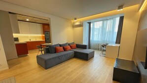 A modern living room with a sectional sofa, a dining area, and a kitchen in the background.
