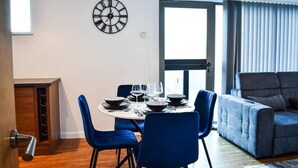 A dining area with a round table, blue chairs, and a clock on the wall. - City Retreat in Manchester (Manchester)