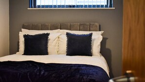 A bedroom with a bed, two pillows, a window with blinds, and a door. - City Retreat in Manchester (Manchester)