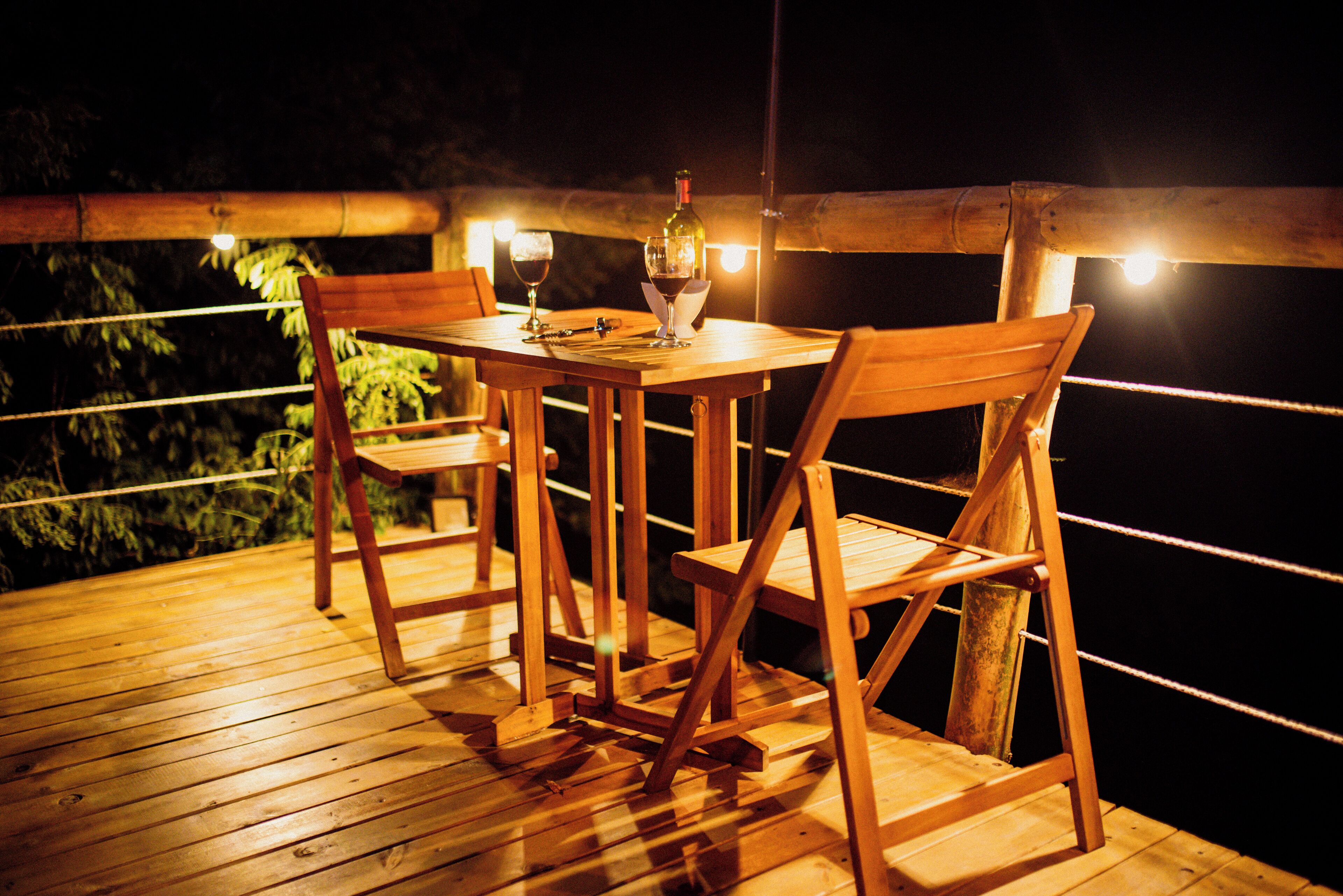 A wooden deck with a table and chairs, a bottle of wine, and glasses.
