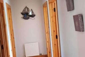 A room with wooden doors, a white radiator, and a wall-mounted decorative sailboat. - Tranquil Retreat at Ailt Cottage- Sleeps13 (Errarooey)
