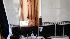 A bathroom with a wooden door, black marble tiles, and a white sink.