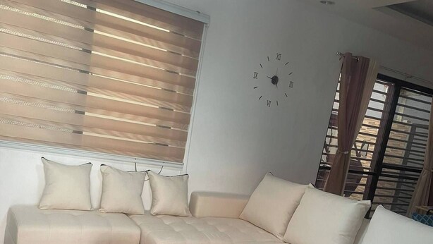 Un salon moderne avec un canapé d’angle, une table basse et une horloge murale.